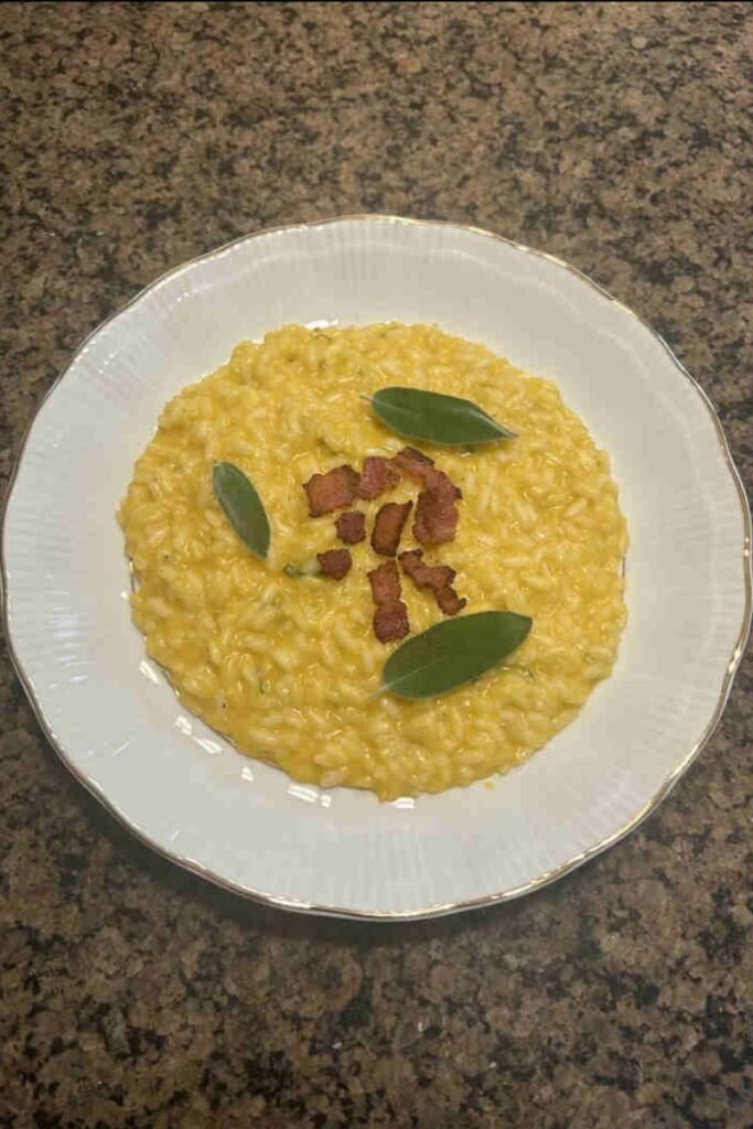 Creamy butternut squash sage risotto served in a bowl, garnished with fresh sage leaves and grated Parmigiano Reggiano cheese.