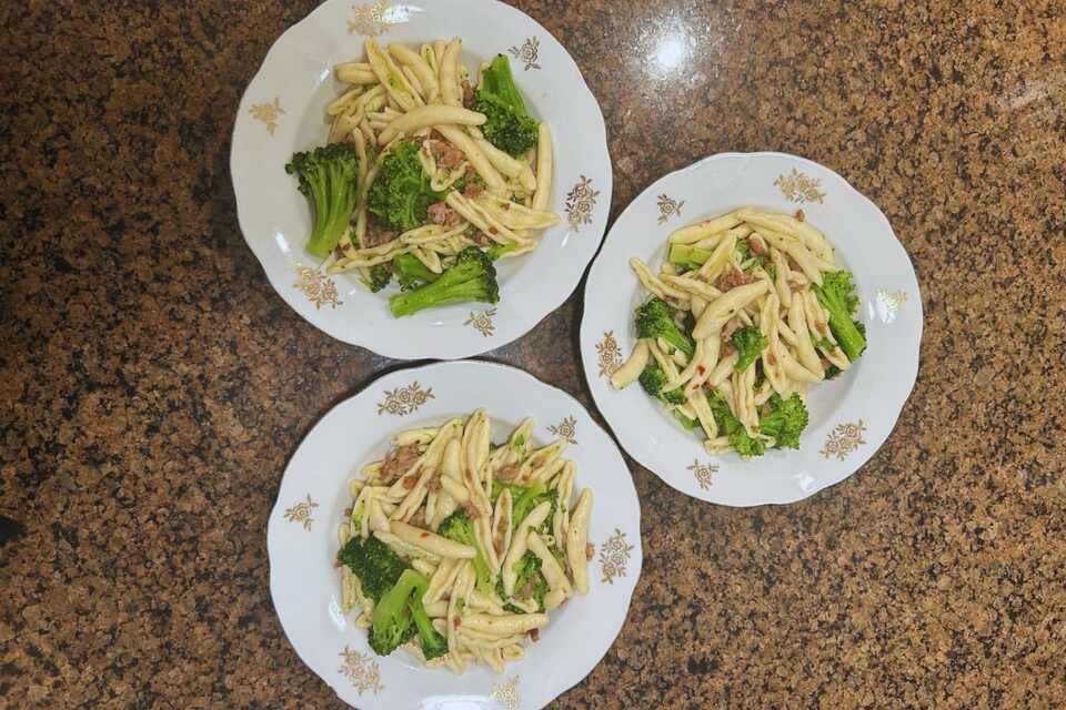 A close-up shot of pasta with broccoli and sausage dinners.