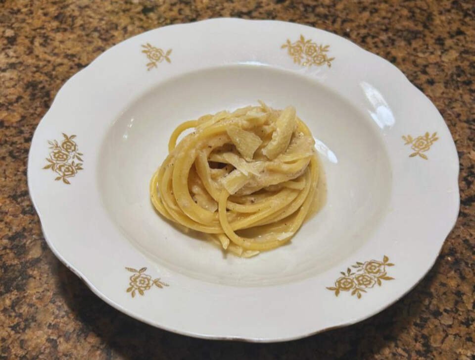 A close-up of a freshly made Cacio e Pepe pasta dish.
