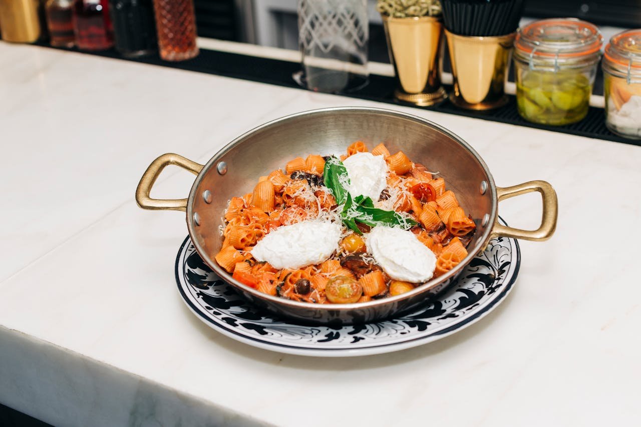 Savor this delectable rigatoni pasta with fresh ricotta and basil garnish, served in a rustic Italian style.