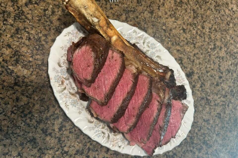 A BBQ tomahawk steak resting in a plate.