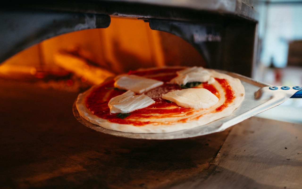 A pizza going into a pizza oven.